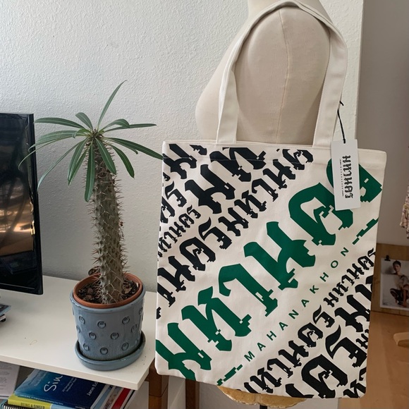 Mahanakhon Tote Bag with green and black font on cream canvas. Pushbutton close - Picture 3 of 6